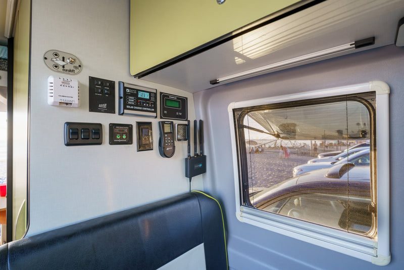 RV rental interior: Control panel displays for solar, inverter, HVAC, and Euroloft bed. Mobile internet and beach window view. — photo 16