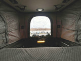 Cozy pop-top interior with a quilted bed, overlooking an RV rental lot. Perfect for travel and camping adventures.