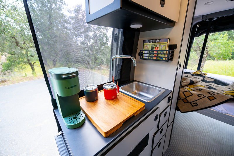 RV rental offers compact kitchen with Keurig, sink, and cozy bed. Perfect for van life adventures! — photo 18