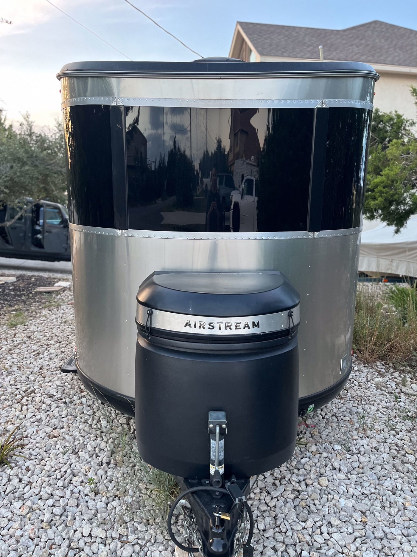 Sleek silver Airstream travel trailer with reflective black front, parked on gravel. Ideal for your next rv rental adventure. — photo 3