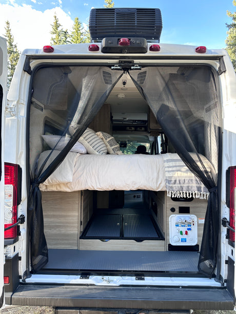 Rear view of an RV rental: a comfy bed, under-bed storage, and bug screen for open-air enjoyment.