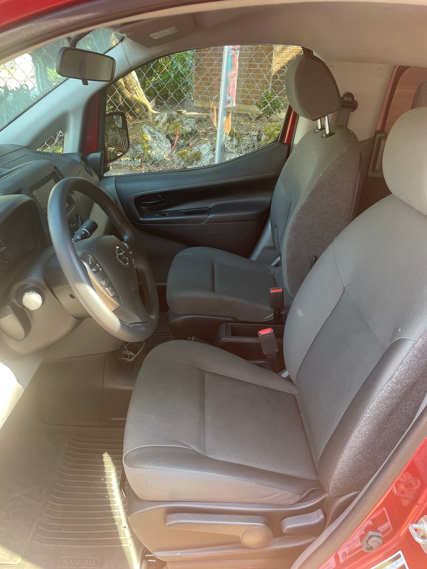 Interior of a Nissan NV200 van, ready for your next rv rental adventure. Shows driver's cockpit, steering wheel, and front seats. — photo 12