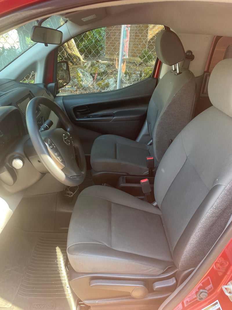 Interior of a Nissan NV200 van, ready for your next rv rental adventure. Shows driver's cockpit, steering wheel, and front seats. — photo 12