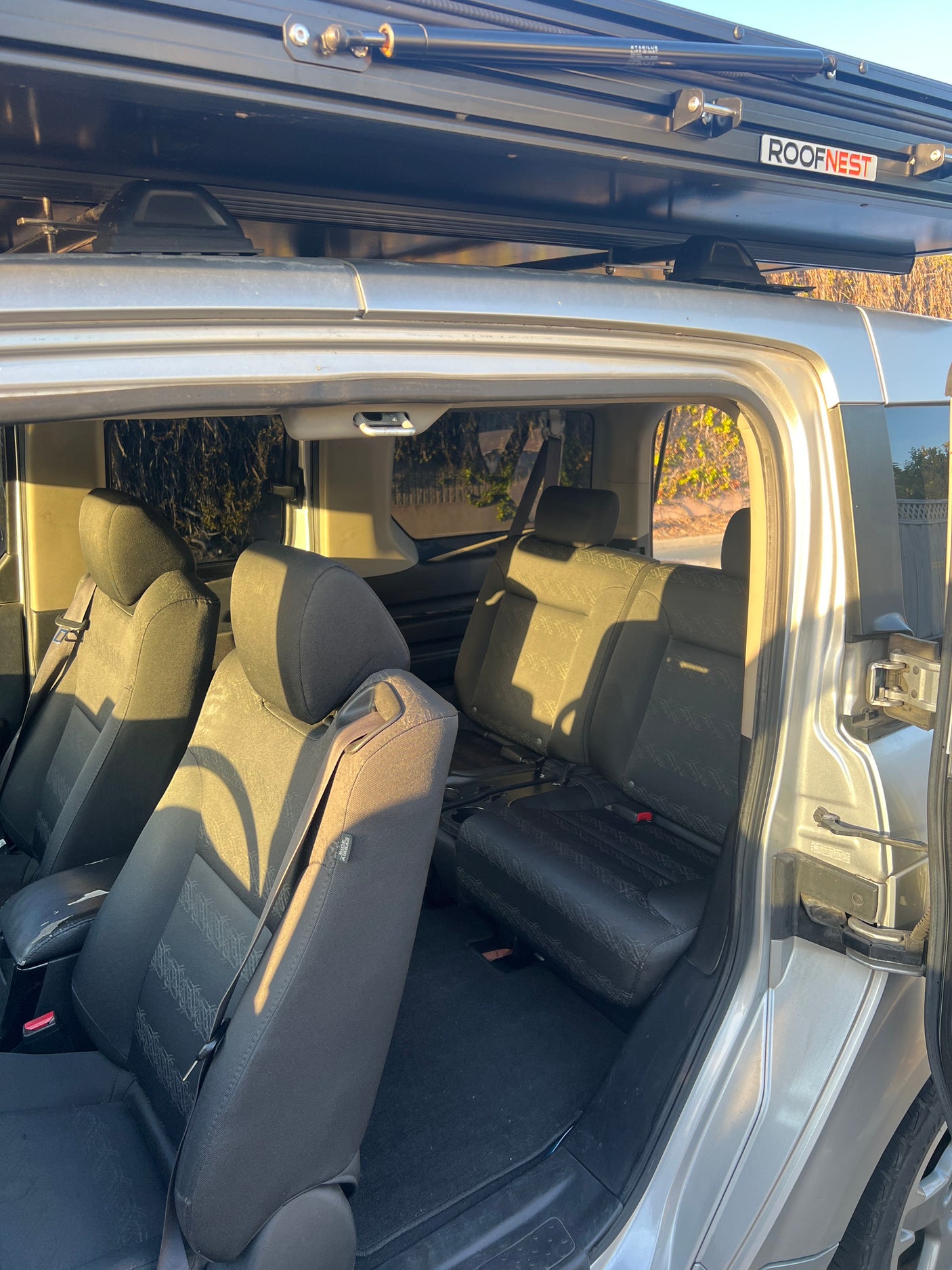 RV rental showing folded rear seats and maximized cargo space, with a ROOFNEST rooftop tent mounted above.
