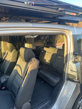RV rental showing folded rear seats and maximized cargo space, with a ROOFNEST rooftop tent mounted above.