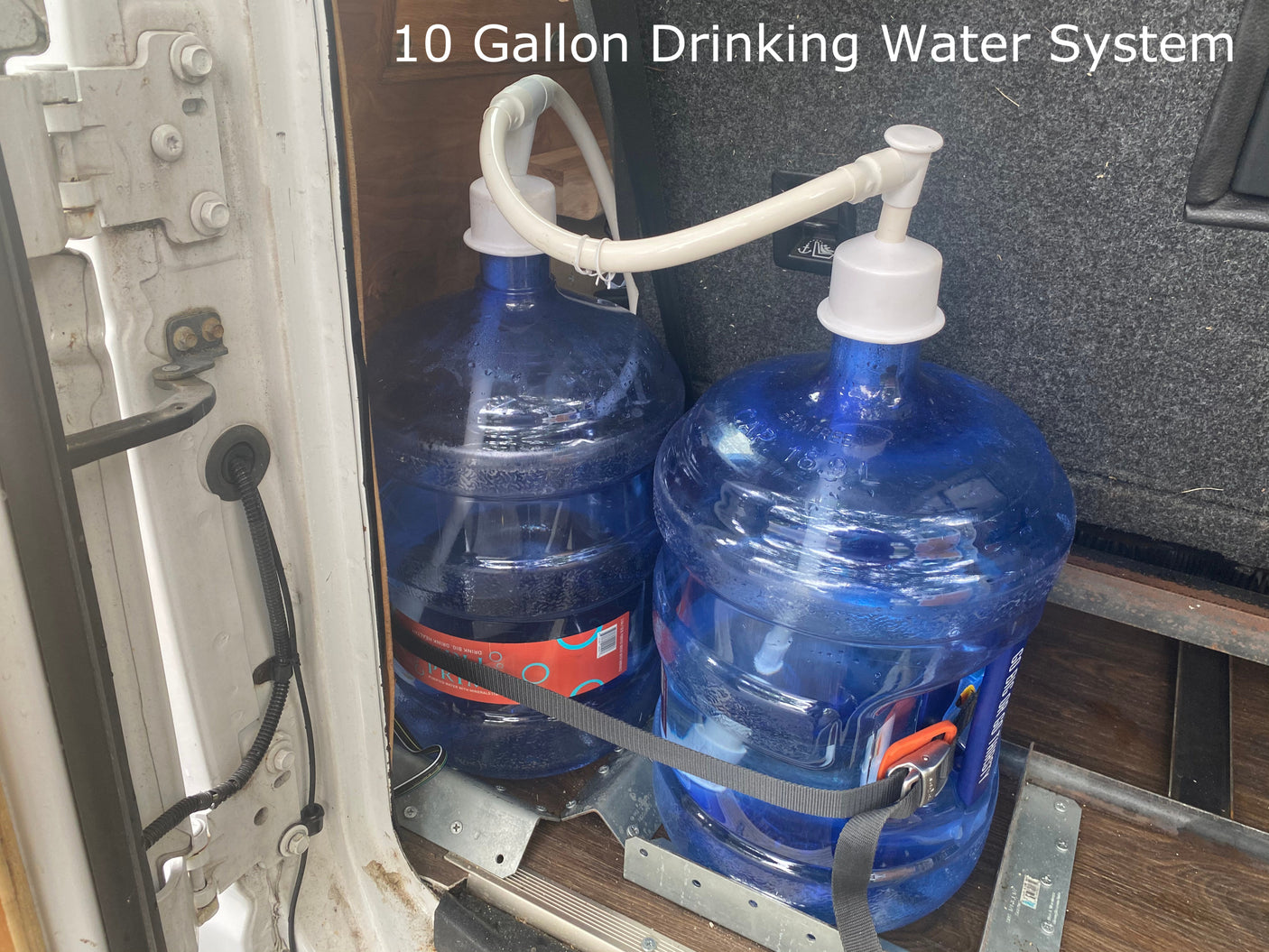 Stay hydrated on your rv rental adventure with this 10-gallon drinking water system, featuring two large blue jugs secured inside a vehicle.