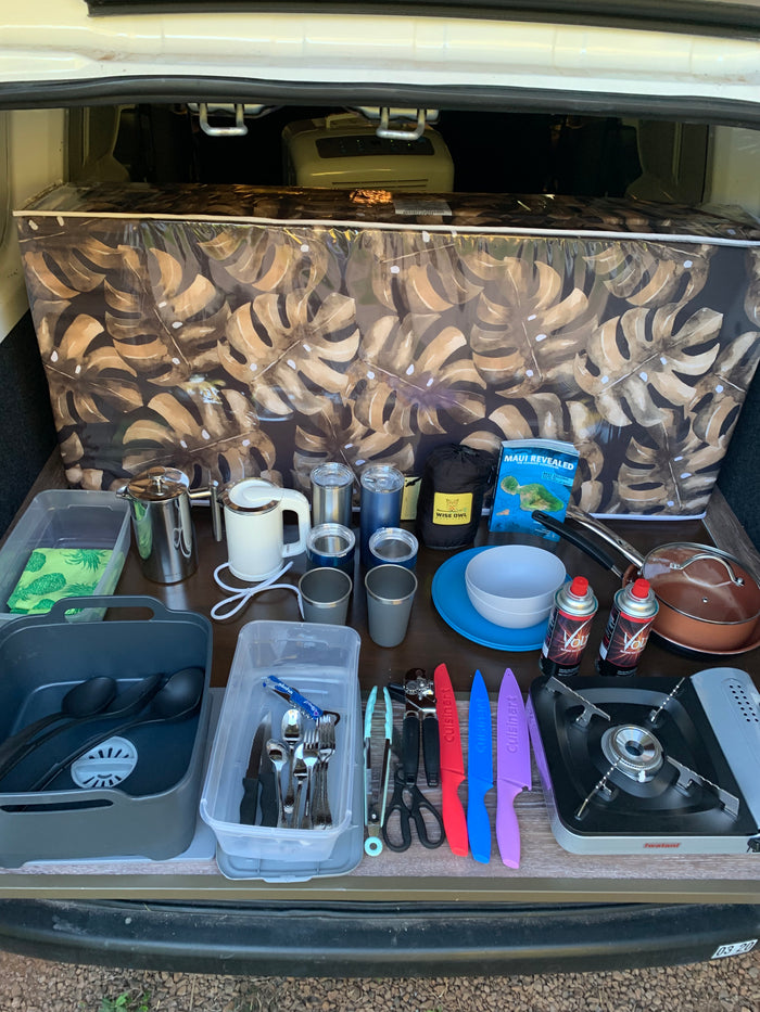 RV rental adventure ready! Organized camper kitchen with stove, pots, cutlery & coffee setup for your outdoor travels.