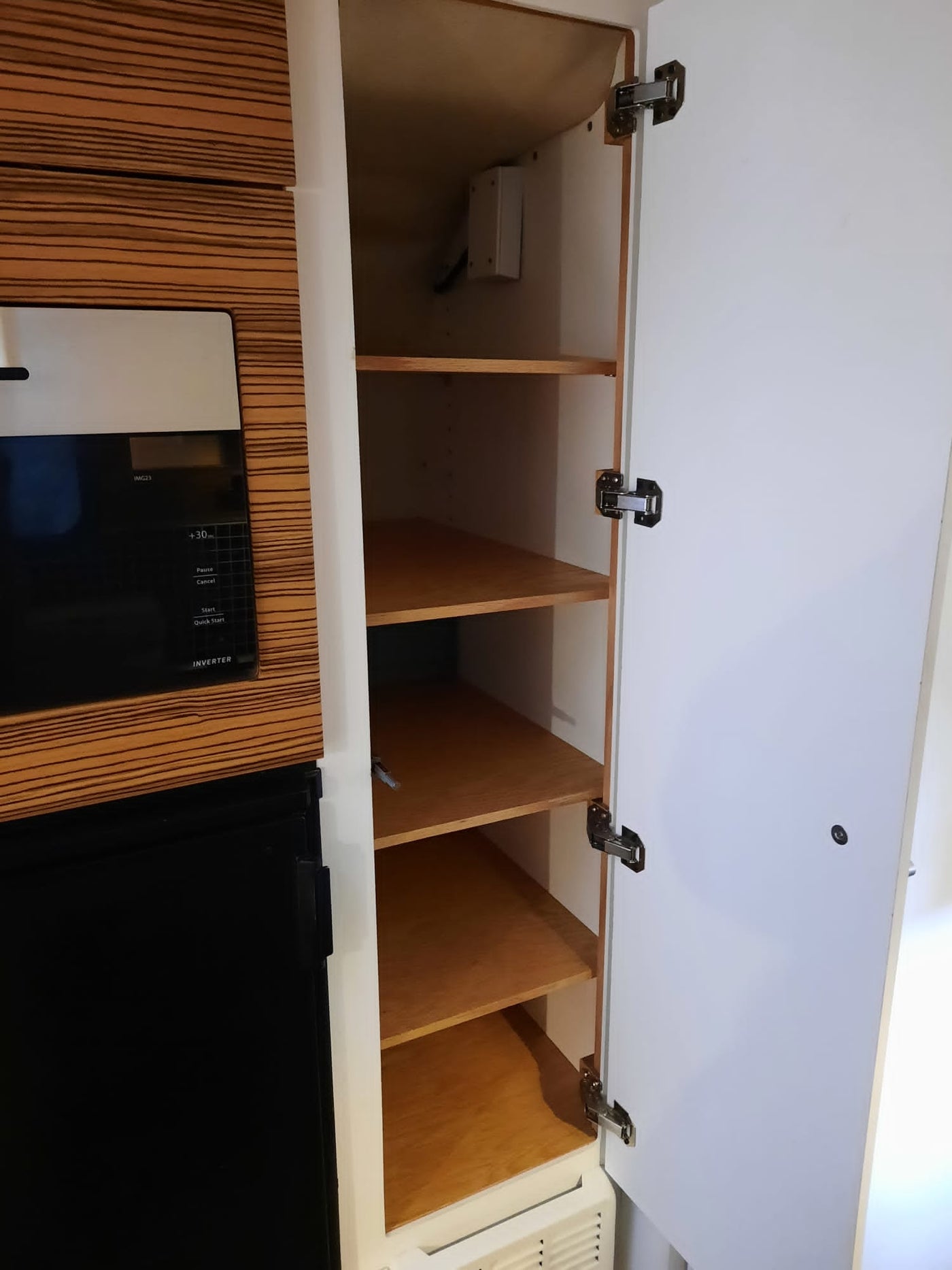 Compact RV rental kitchen features a built-in microwave, mini-fridge, and an open cabinet with versatile storage shelves. — photo 15