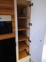 Compact RV rental kitchen features a built-in microwave, mini-fridge, and an open cabinet with versatile storage shelves.