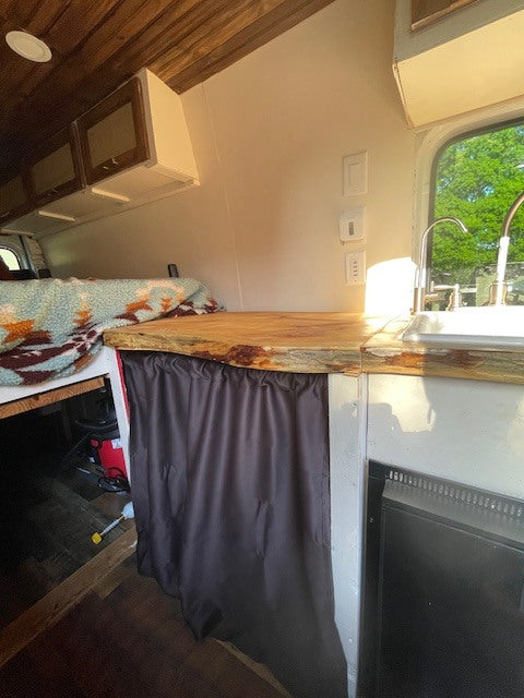 Step inside this RV rental! Features a rustic wood ceiling, compact kitchen with sink, comfy bed, and clever storage.