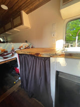 Step inside this RV rental! Features a rustic wood ceiling, compact kitchen with sink, comfy bed, and clever storage.
