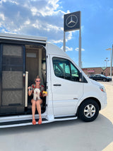Woman & dog in their new Mercedes RV, holding keys & a 'SOLD' sign. Ready for the open road, perfect as an rv rental!