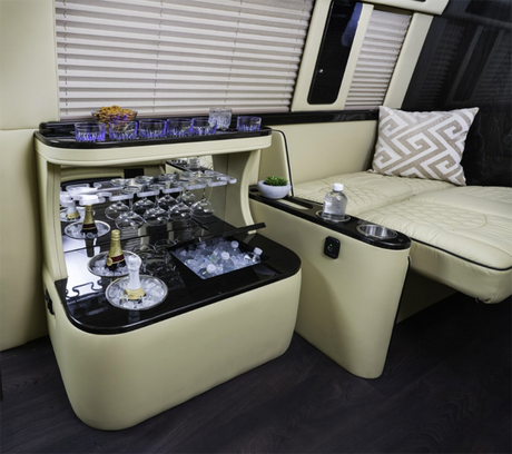 Experience luxury in this RV rental: lavish interior with a built-in bar, chilled drinks, glassware, and plush seating.