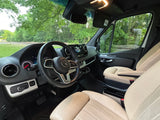 Spacious Mercedes-Benz Sprinter van interior, likely an RV rental, showing dashboard, steering wheel, and cream seats. Train tracks outside.