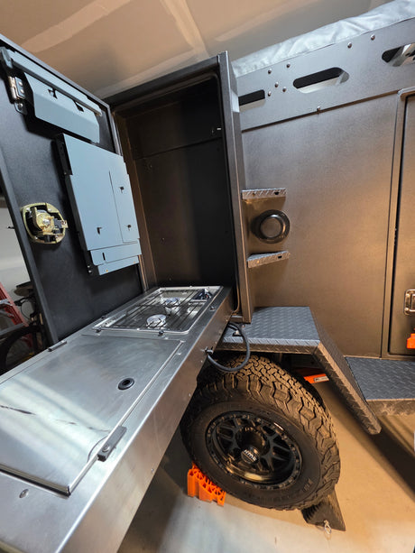 Rugged off-road RV rental with an extended outdoor kitchen. Features a two-burner stove and stainless steel counter for camping.