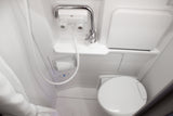 Inside an RV rental, this compact wet bath features a toilet, shower hose, and versatile faucet for efficient use.