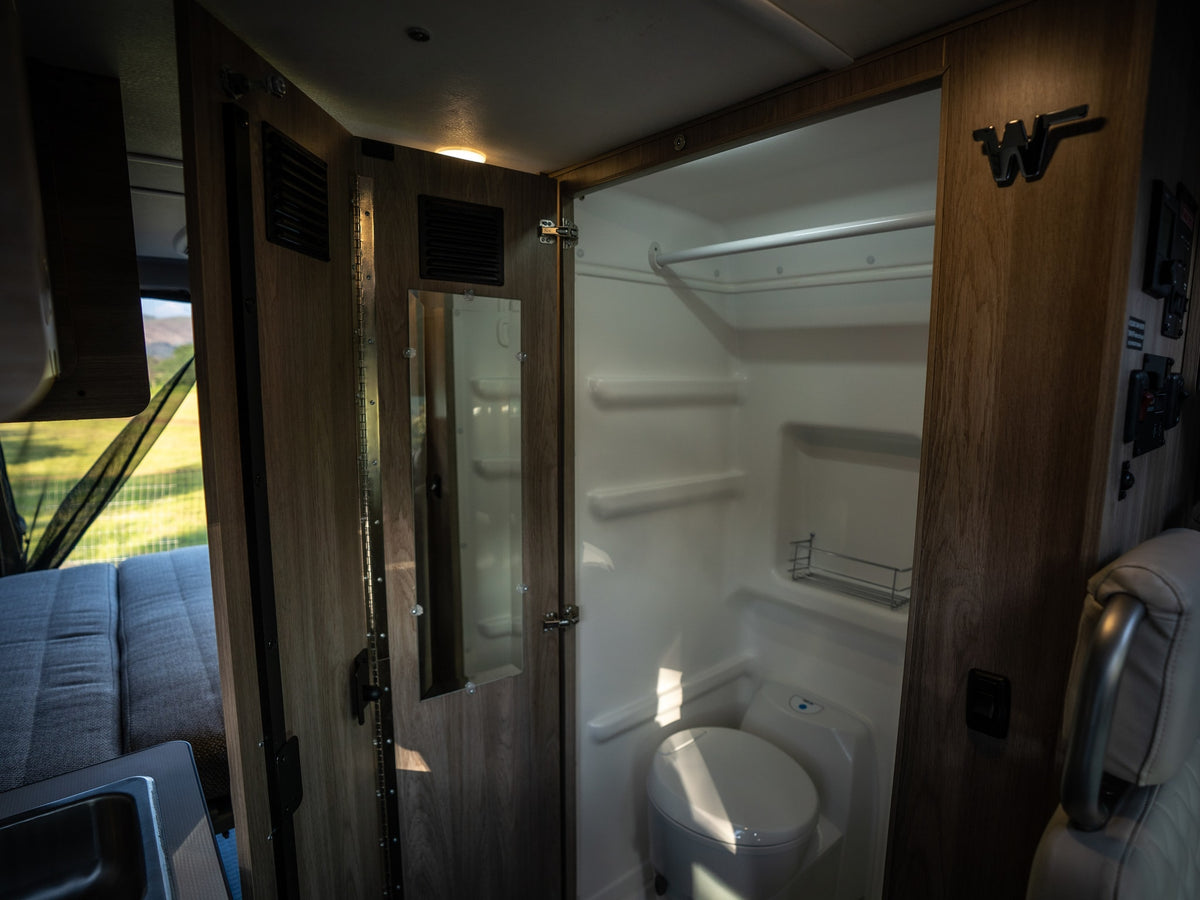 Step inside this RV rental: a well-designed compact bathroom with toilet and shower, featuring a mirrored door and efficient layout. — photo 11