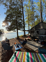 Lakeside RV rental camping with friends, a warm campfire, and beautiful sunset reflections over the water. Perfect outdoor escape!