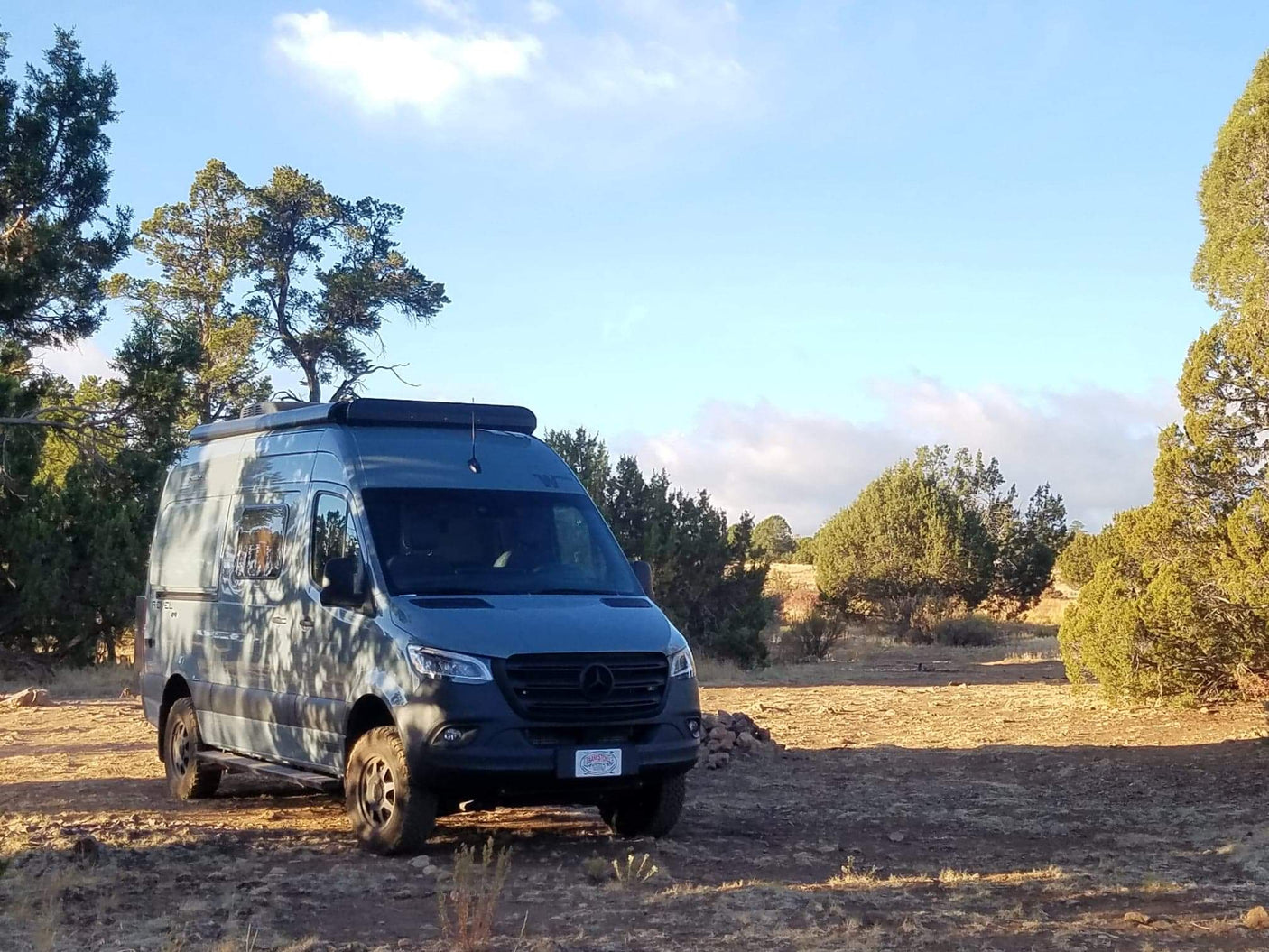 Gray Mercedes Sprinter camper van for rv rental in a scenic, dry landscape under a blue sky. Ready for adventure!