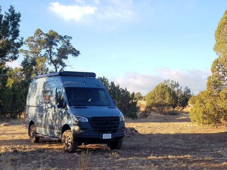Gray Mercedes Sprinter camper van for rv rental in a scenic, dry landscape under a blue sky. Ready for adventure!