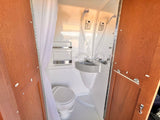 RV rental compact wet bath: a functional space featuring a toilet, small sink, and shower within a single enclosure.