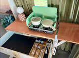 RV rental's compact kitchen offers a two-burner stove with cookware and an organized pull-out drawer for utensils.