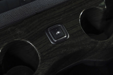 RV rental interior: power liftgate button and cup holders on the dark wood grain console for convenience.
