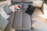 RV rental interior: Comfortable seating, two Hello Kitty plushies, and a laptop. Enjoy cozy travel comfort.