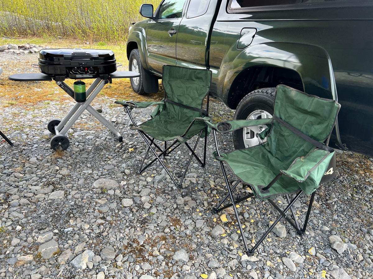 A green pickup truck, black portable grill with a propane tank, and two green camping chairs on gravel. Ideal for rv rental trips. — photo 10