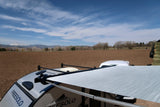 Freesolo RV rental: a trailer with an open awning overlooks a vast plowed field and distant snow-capped mountains.