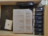 RV rental kitchen drawer with neatly stacked spices, salt, a stapler, playing cards, and a folded towel.