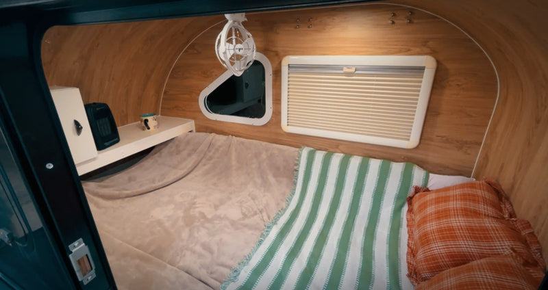  featuring outdoor cooking gear and vibrant autumn leaves.|Person cooking breakfast on a portable stove outdoors. Fall foliage in background. Great for your next rv rental camping trip!|Compact rv rental interior showing a cozy sleeping area with wood paneling — photo 7