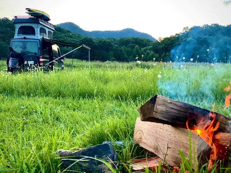 Experience nature with an rv rental. Camper van in a grassy field with mountains, a warm campfire glowing. — photo 7
