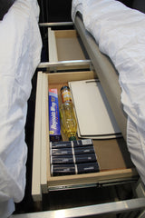 Compact kitchen supplies: foil, oil, cutting board, and spices neatly organized in an RV rental under-bed drawer.