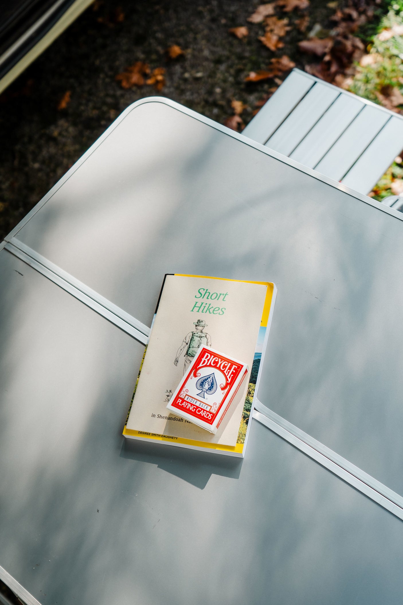 RV rental trip essentials: "Short Hikes" guide and playing cards ready on a camp table for outdoor adventure.