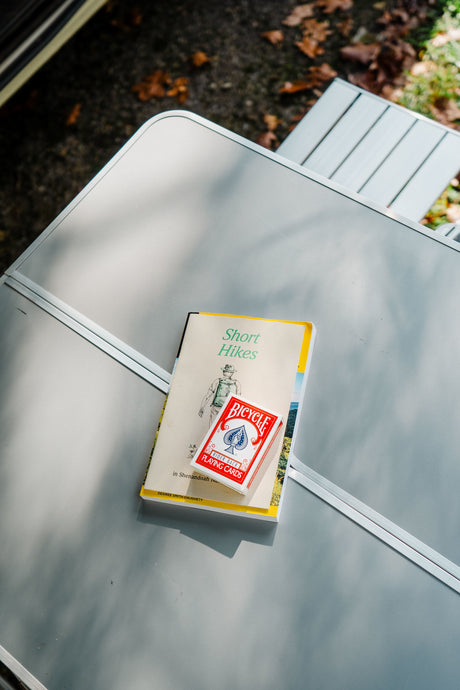RV rental trip essentials: "Short Hikes" guide and playing cards ready on a camp table for outdoor adventure.