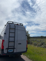 White camper van with ladder and roof rack, an ideal RV rental for a road trip through nature.