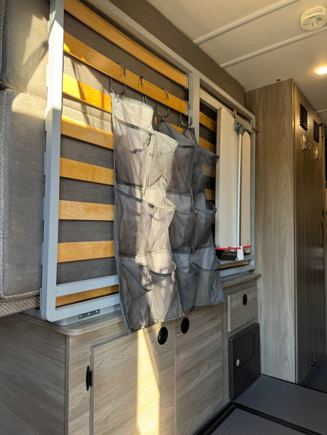 Inside this RV rental: folded bed with mesh storage, cabinets, and a compact table. Ideal for maximizing space on the go.
