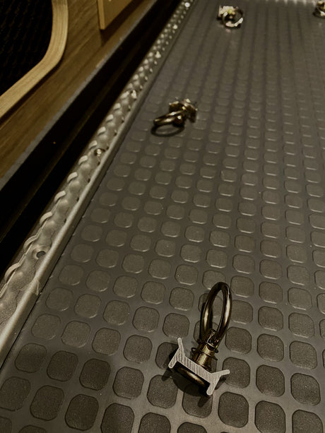 RV rental cargo area with L-track single stud tie-downs & textured floor mat for securing your gear.