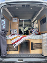 Cozy camper van interior: bed, storage, & kitchen area, ready for an RV rental adventure.