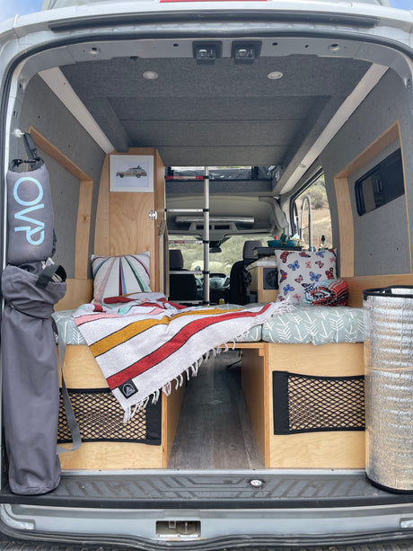 Cozy camper van interior: bed, storage, & kitchen area, ready for an RV rental adventure.