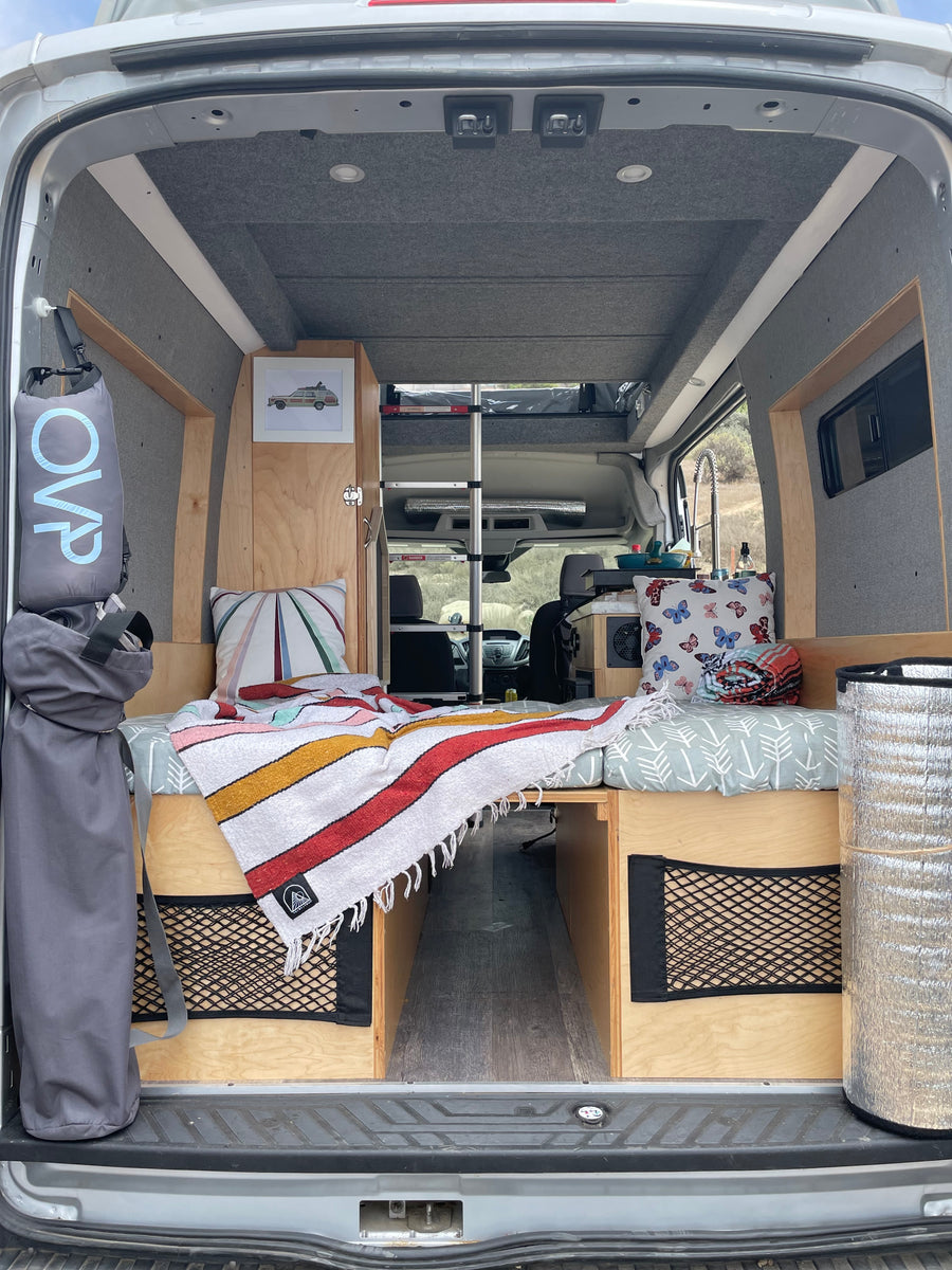Cozy camper van interior: bed, storage, & kitchen area, ready for an RV rental adventure.
