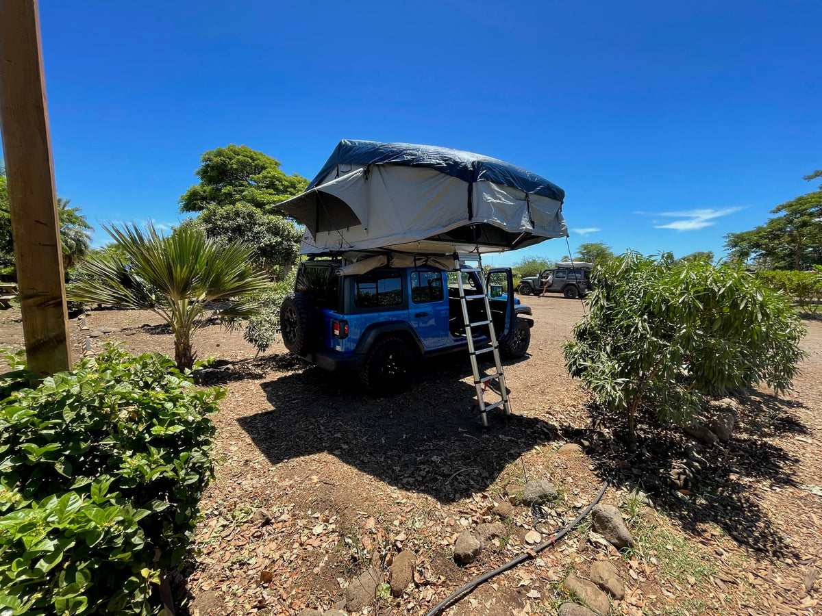 Bright blue Jeep Wrangler with a deployed rooftop tent and ladder, an ideal RV rental for your next outdoor adventure. — photo 19