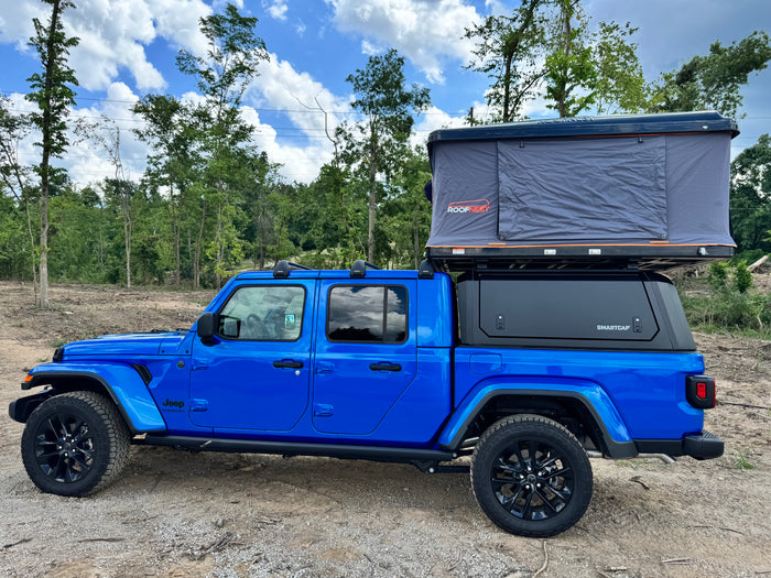 Bright blue Jeep Gladiator pickup with a SmartCap & Roofnest rooftop tent, ideal for your next rv rental adventure.