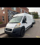 White Ram ProMaster van, likely an RV rental, parked on a city street beside a building with a floral mural.