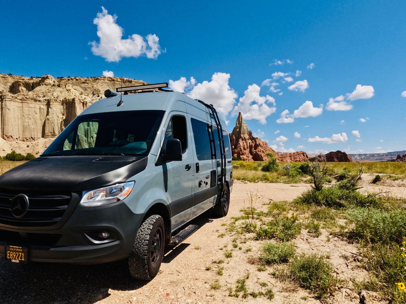  surrounded by Joshua trees and warm lights.|Light grey Mercedes Sprinter RV rental parked on a dirt road — photo 3