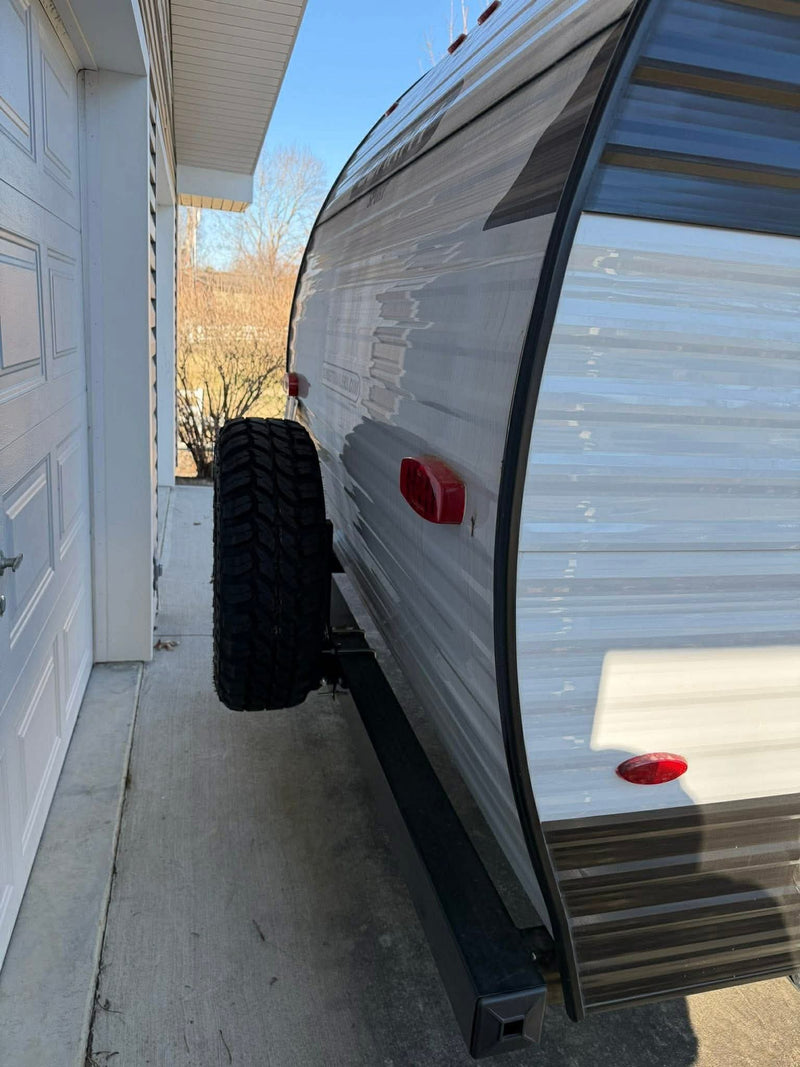 Compact RV rental parked tight beside a garage, with a rear-mounted spare tire visible on the travel trailer's side. — photo 10
