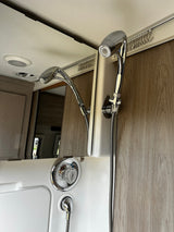 RV rental shower: modern chrome fixtures, flexible hose, and curtain track, showcasing a functional, compact bathroom interior.