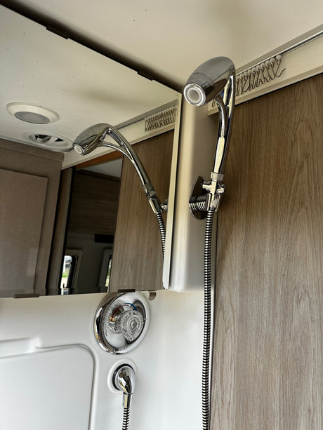 RV rental shower: modern chrome fixtures, flexible hose, and curtain track, showcasing a functional, compact bathroom interior.