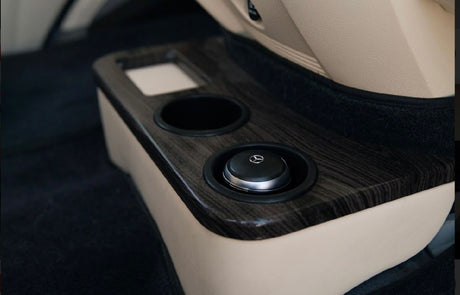 RV rental interior: Dark wood grain console with a cup holder and a Mercedes control knob, plush beige upholstery.